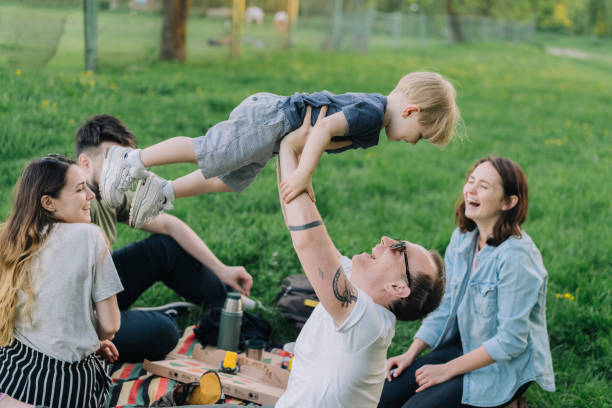 istock Group of  young people playing with little boy on picnic 967697342