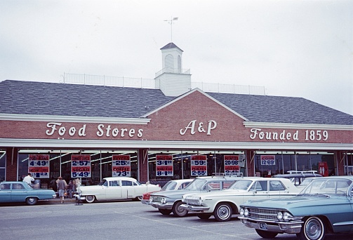 Washington DC, USA, 1964. A food store owned by A & P in Washington DC. Furthermore: parked cars, offers and consumers.