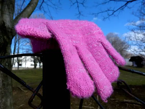 pink knitted girl's glove left on a wire fence by a kindergarten