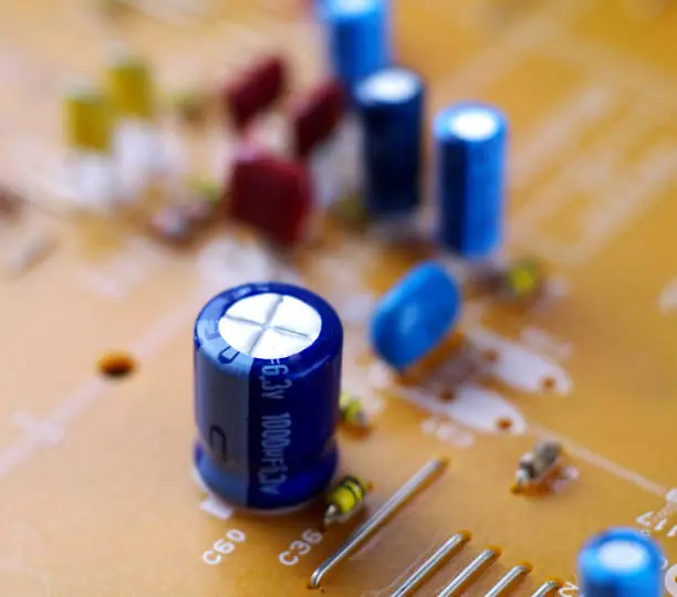 Photo of electrolytic capacitor on printed circuit board, macro, selective focus