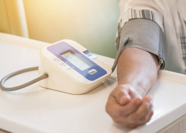 paciente, verificação de pressão arterial usando o braço superior tensão arterial monitor equipamentos médicos na sala de exames da clínica - stroke vascular symptoms patient - fotografias e filmes do acervo