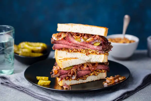 Roast beef sandwich on a plate with pickles. Copy space