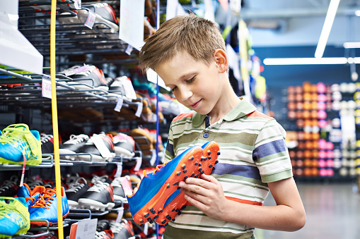 Boy with soccer shoes in the sports store