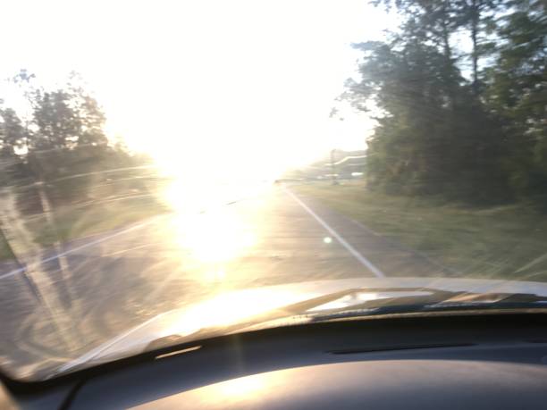 istock Driver's impeded view of road while facing blinding sunrise through dirty windshield 967743822