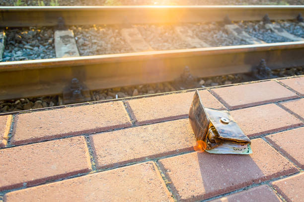 el concepto de dinero perdido es una billetera de cuero perdido con dinero en la acera del ferrocarril treck. - oficina de objetos perdidos fotografías e imágenes de stock