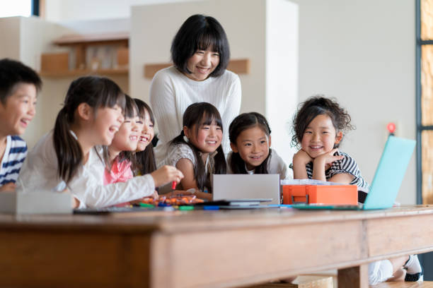 istock Young group of students looking at a laptop with their teacher 967766022
