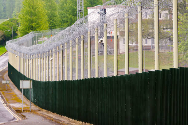 istock Prison fence with coiled razor wire and CCTV Cameras 967774222
