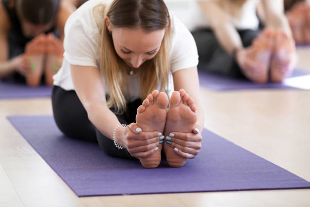 istock Group of young sporty people in paschimottanasana pose 967775230