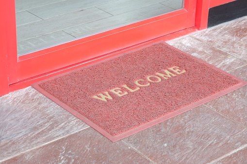 old welcome text on red doormat in front of door