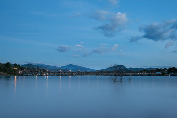 Landscape of Uttamanusorn Bridge or Mon Bridge with reflection on river and blue sky in the evening at Sangkhlaburi district,Kanchanaburi province,Thailand. Thailandâs longest wooden bridge and the second longest in the world. paisaje de uttamanusorn puente o puente de mon con reflexión sobre río y azul cielo en la noche en el distrito de sangkhlaburi, provincia de kanchanaburi, tailandia. más largo puente de madera de tailandia y el segundo más largo del mundo.