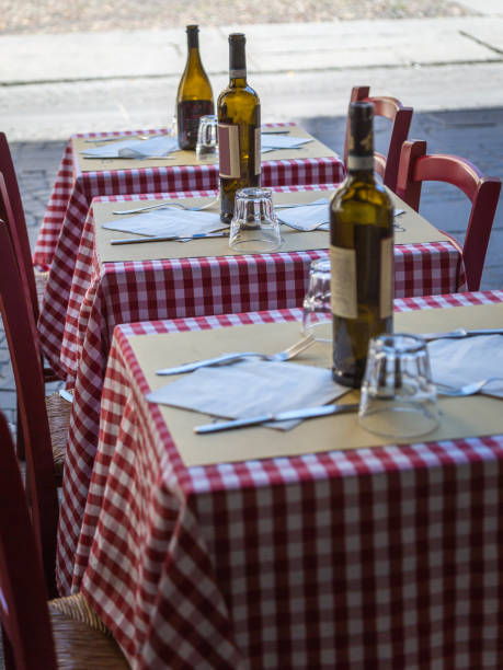 istock Three Little Wooden Tables Set with Red Checked Tablecloth, Wine Bottles and Cutlery 967789132