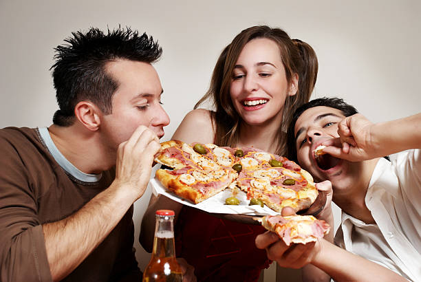 Young friends eating a pizza and drinking beer stock photo