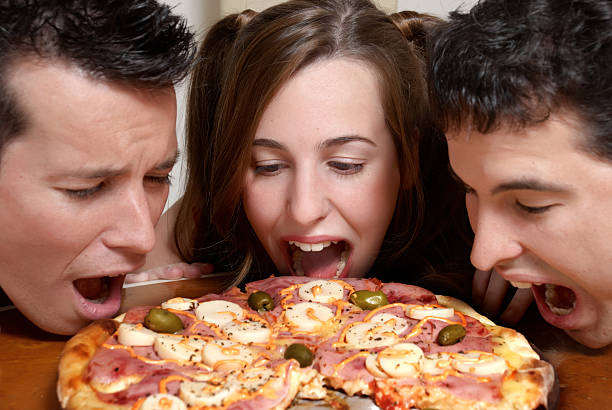 The cheerful company of youth eating a pizza stock photo