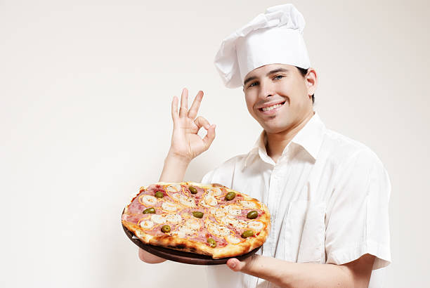 Portrait of happy attractive cook with a pizza in hands stock photo