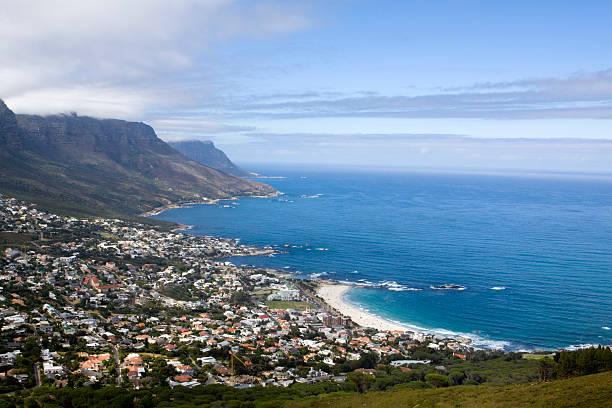 Camps bay town, and the Twelve Apostles mountain range, a shot from on atlantic ocean with rocks at Fourth Beach, Clifton, Cape Town, South Africa