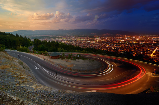Day and Night. Light streaks over road and Skopje city in distance, Macedonia. Photo manipulation.