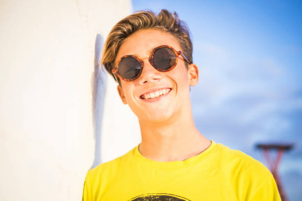 beautiful and wonderful nice young model 14 years old pose and smile to the camera under the sunlight. vacation and happiness concept wih blonde boy - teenager 14 15 years 13 14 years cheerful imagens e fotografias de stock