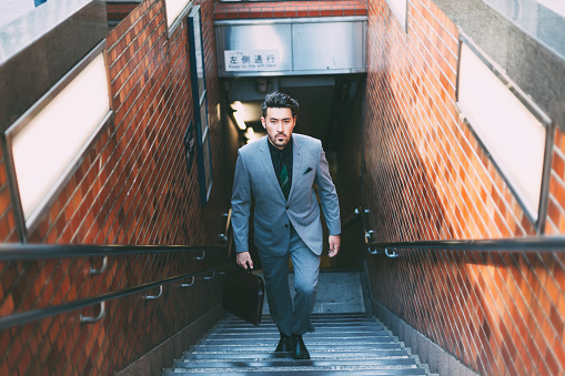 A young Japanese businessman is leaving the subway to go to work in Tokyo.