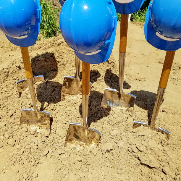 blue hardhats on shovels in dirt stock photo