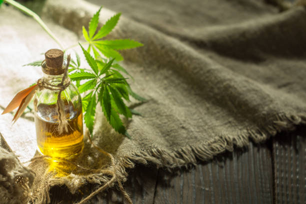 istock Hemp oil, canvas and threads on a dark wooden surface 967916108
