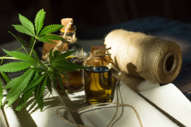 istock Hemp oil, canvas and threads on a dark wooden surface 967917314