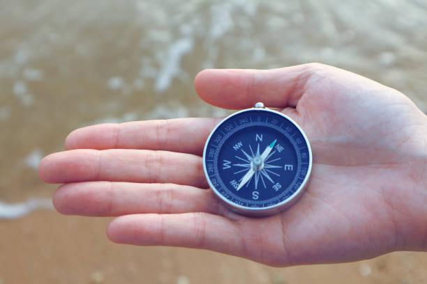 istock Compass in the hand with sea background. 967935164