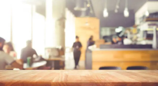 Photo of Wood table top with blur of people in coffee shop or (cafe,restaurant )background