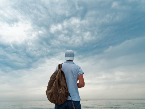 Tourist is on the beach in cloudy weather while exploring Sochi, Russia. Uncertain gender. Rear view