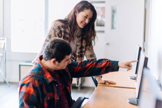 istock A female teacher helping a male student on a computer 967953598