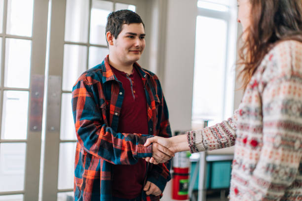 A young female social worker from social services greeting a young teenager boy stock photo