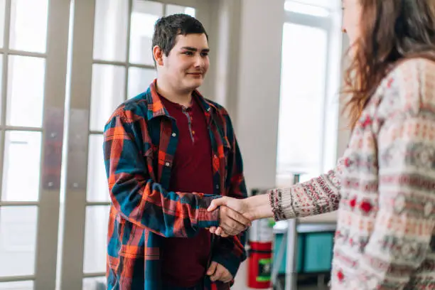 Photo of A young female social worker from social services greeting a young teenager boy