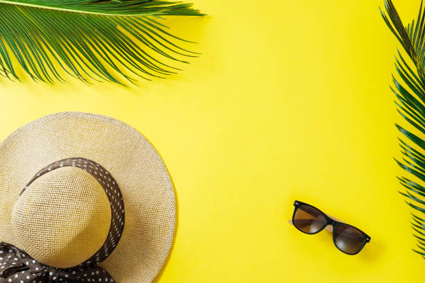 istock Travel concept: hat, palm leaf and sun glasses on yellow background. Top view, flat lay, space for text 967953814