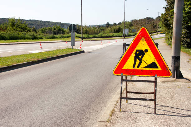 Road works sign for construction works in city street. Road under construction traffic sign. Traffic, warning sign road repairing. Outdoor street sign. Red, black and yellow triangle road sign work. muestra de obras para la construcción de obras en calle de la ciudad. camino bajo la señal de tráfico de la construcción. tráfico, advertencia señal reparación de carretera. cartel de calle al aire libre. rojo, negro y amarillo el triángulo carrete