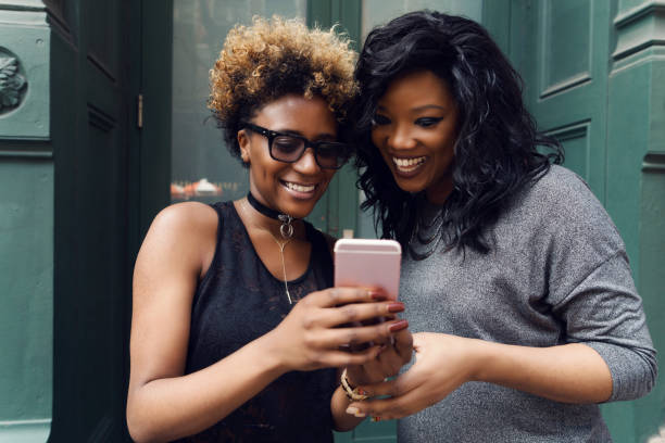 istock Female friends using mobile phone on street 967972170