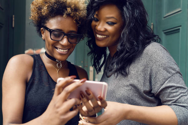 istock Female friends using mobile phone on street 967972174