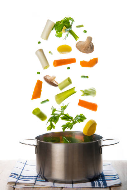 verdure fresche che cadono in una pentola isolata su uno sfondo bianco - minestrone foto e immagini stock