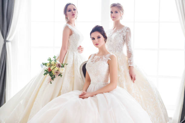 Three young woman with bouquets wearing wedding dresses