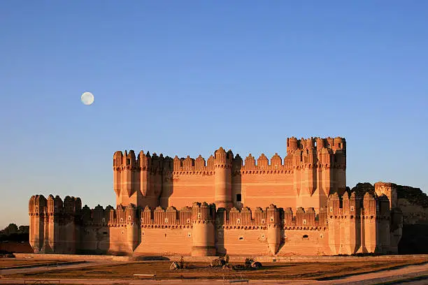 Photo of The fortress of Coca (Spain) at dusk with full moon