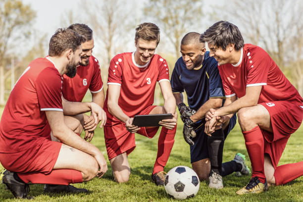 una squadra di calcio che guarda le tattiche su un tablet durante una sessione di allenamento di calcio - strategy coach soccer digital tablet foto e immagini stock