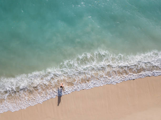 istock Woman with surfboard walking through sea foam 968009168