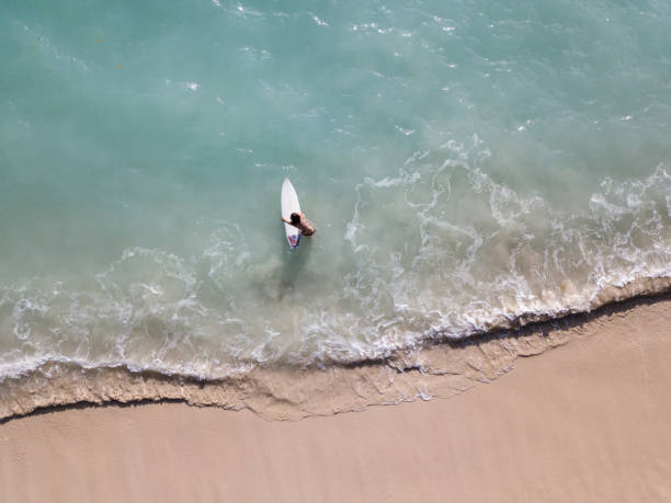 istock Woman in bikini putting her surfboard in the ocean 968009196
