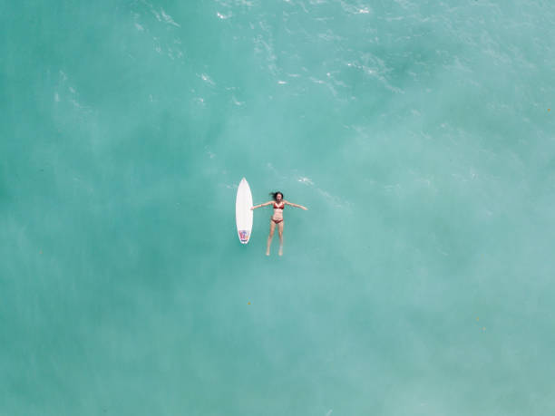 istock Young woman floating in the ocean with a surfboard 968009268