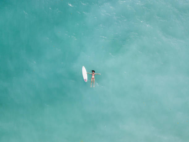 istock Young woman floating in the ocean with a surfboard 968009282