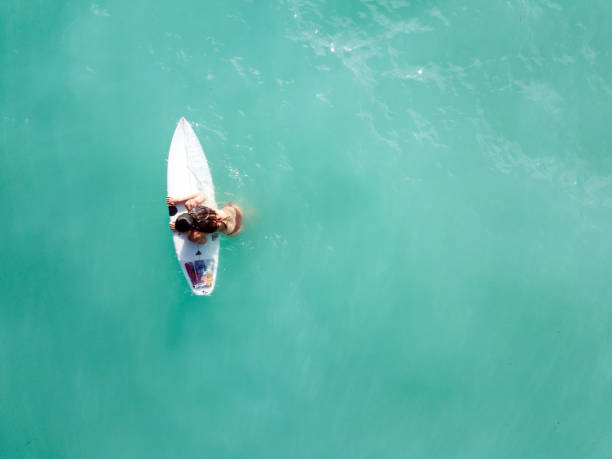 istock Young woman climbing on a surfboard in the ocean 968009304