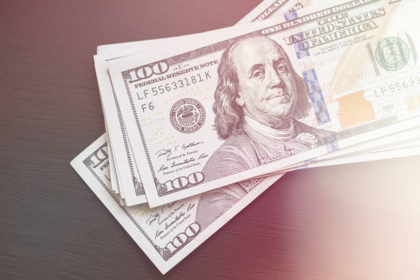 istock Light toning New US hundred-dollar bills on a black wooden textured table. Vi 968011806