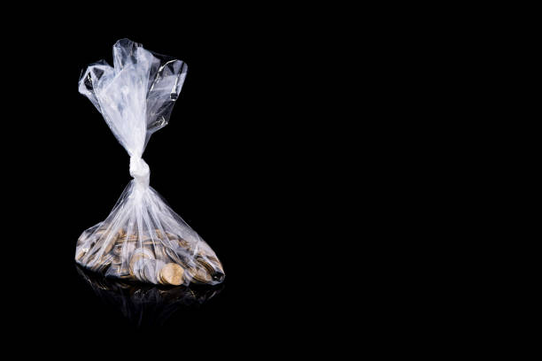 Group of coins in a polyethylene package, isolated on a black background with reflection. Ukrainian money