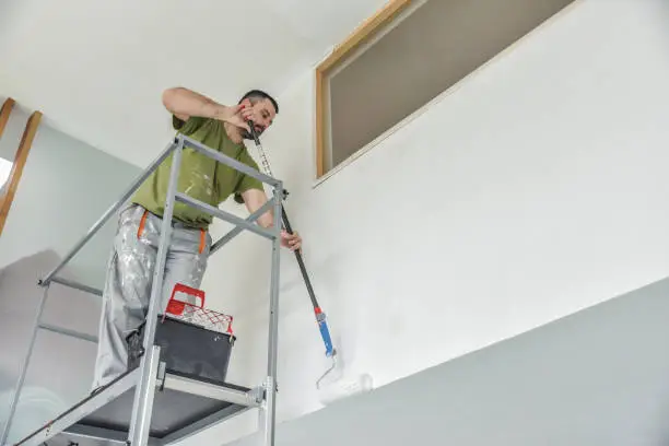 Profesional painter painting with paint roller.
Decorator at work painting a wall.