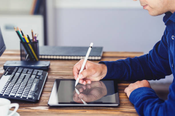 istock Man Working on Computer in Office Room with Digital Tablet and Stylus 968016956