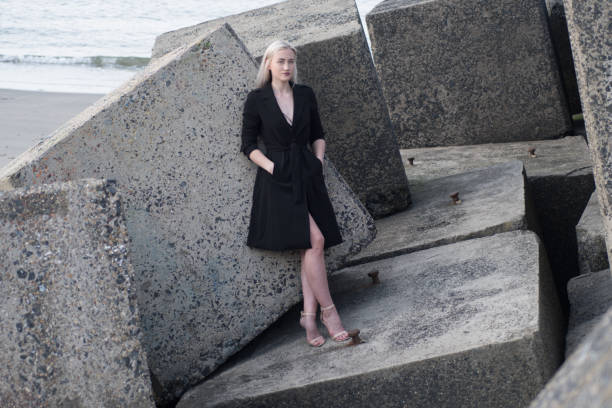 istock blonde girl in black coat on stones 968019638