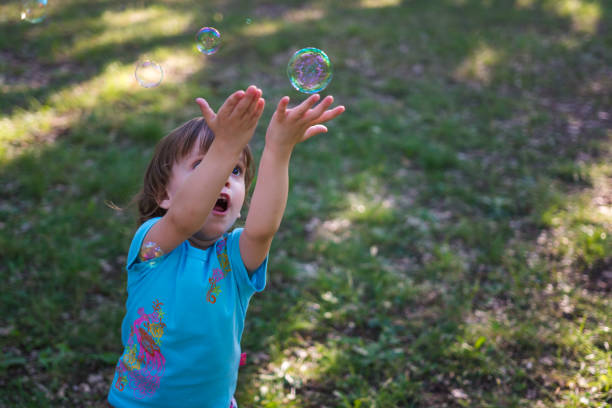 istock Little girl playing with soap bubbles 968022430